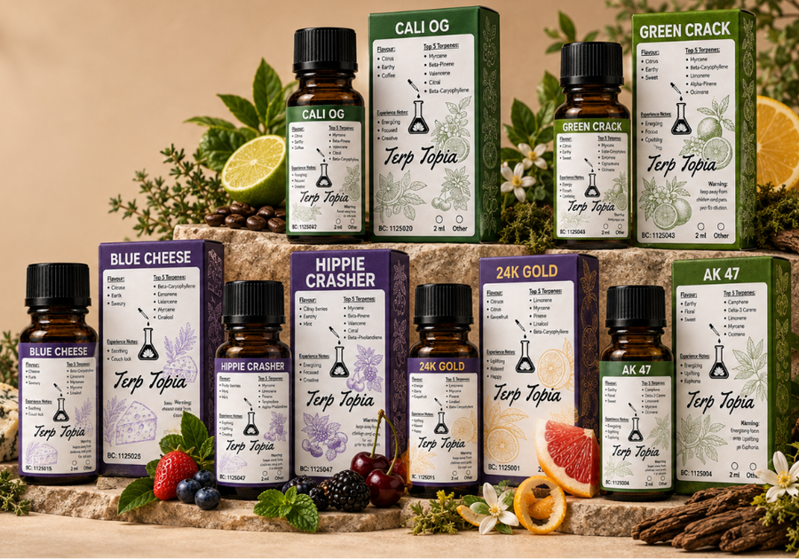 A styled product display of multiple Terp Topia oil bottles and matching retail boxes arranged on a stone surface with herbs, citrus slices, fruit, and cheese as props. Visible labels include Cali OG, Green Crack, Blue Cheese, Hippy Crasher, 24K Gold, and AK 47.